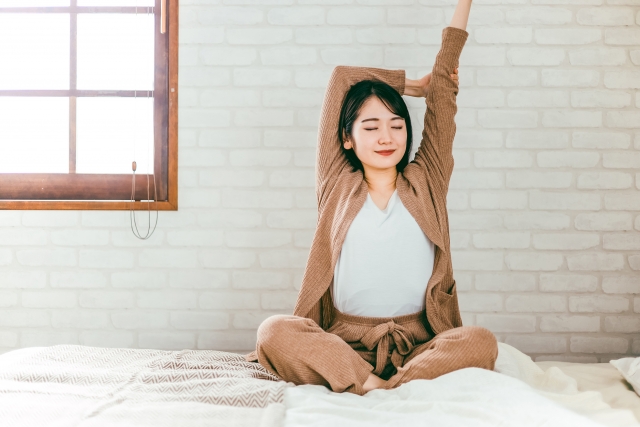 ベッドでストレッチをする若い女性